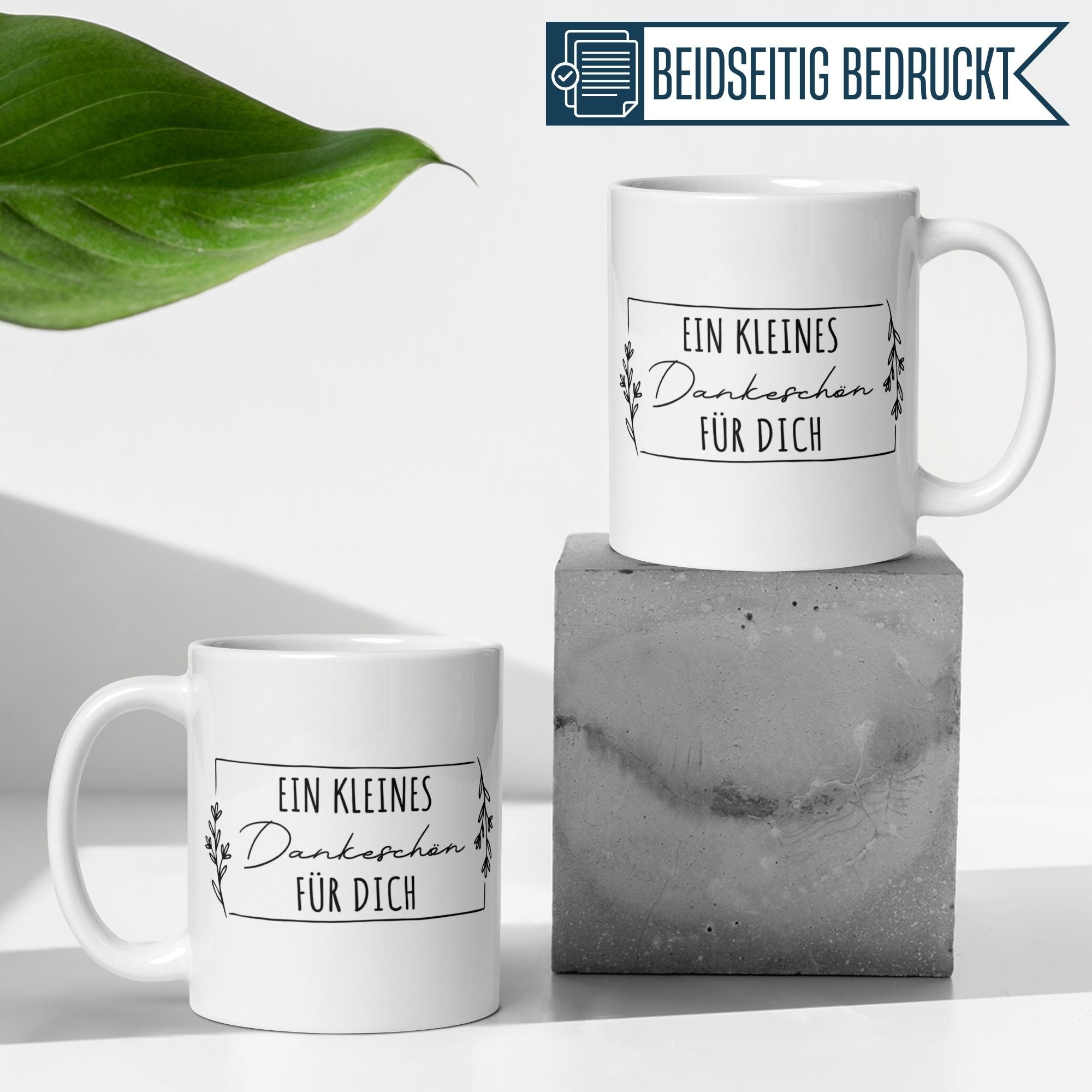 Zwei elegante Tassen mit dem Spruch 'Ein kleines Dankeschön für dich' auf stylischem Hintergrund.