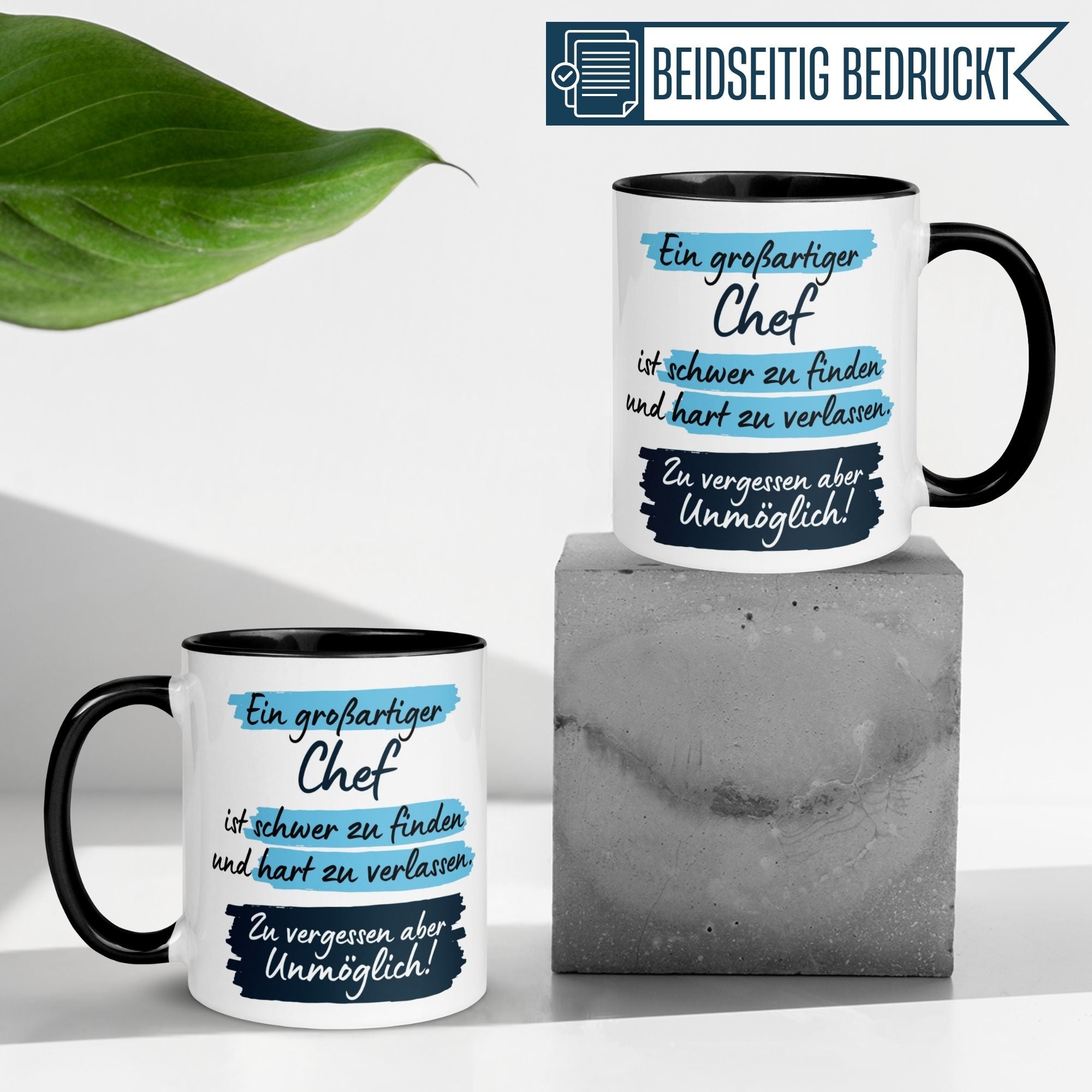 Zwei beidseitig bedruckte Tassen mit Spruch über einen großartigen Chef, platziert auf einem modernen Untergrund.