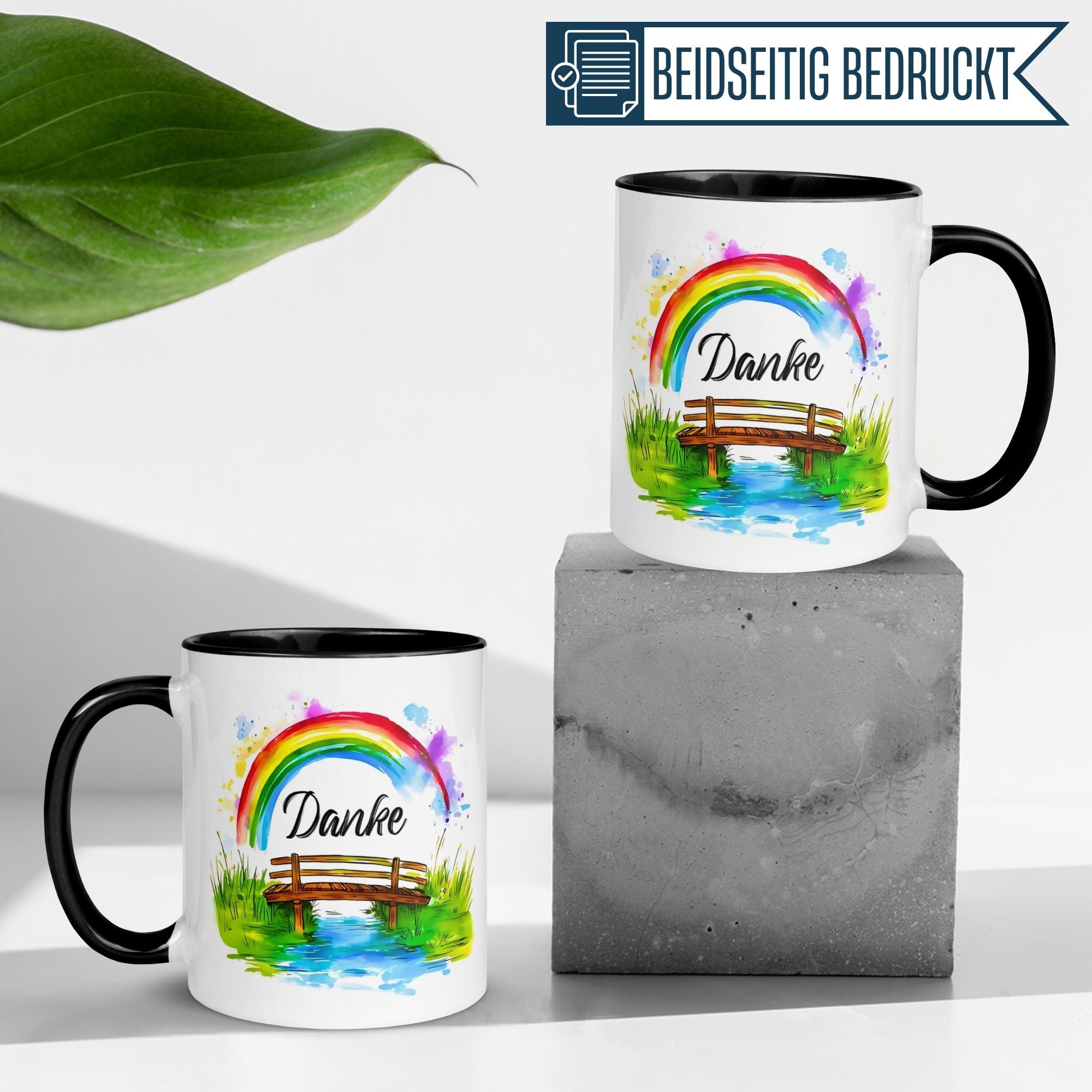 Momentals Tasse Danke mit Regenbogenmotiv auf Betonuntergrund, beidseitig bedruckt für stilvolle Wertschätzung.