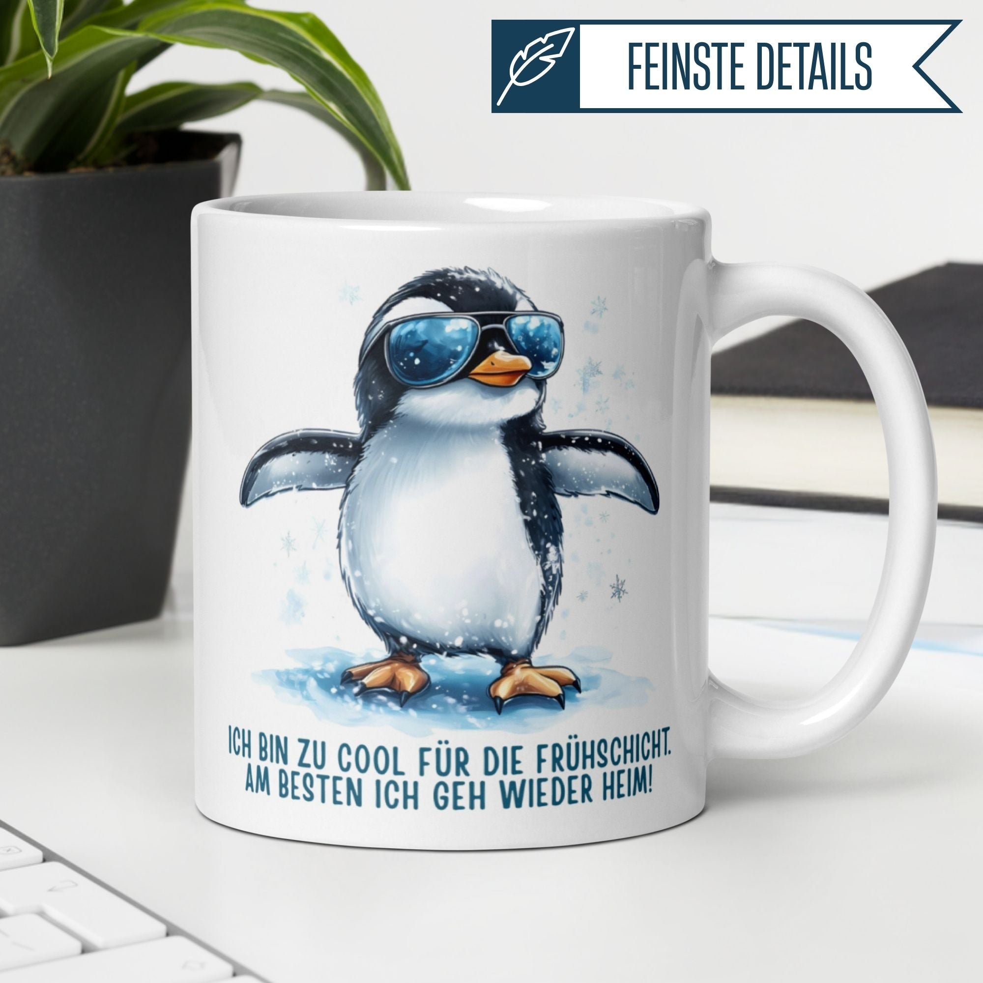 Momentals Tasse mit Pinguin und Spruch "Zu cool für die Frühschicht" auf einem Schreibtisch.