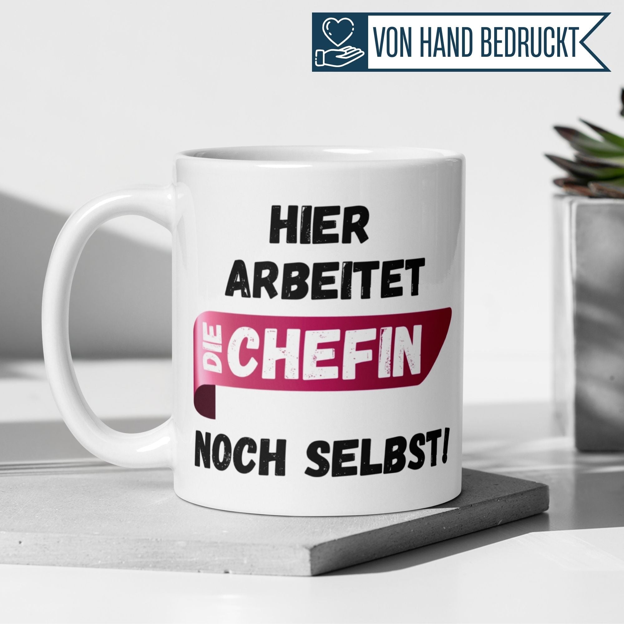 Weißer Kaffeebecher mit pink-schwarzer Aufschrift: "Hier arbeitet die Chefin noch selbst!" für Führungskräfte