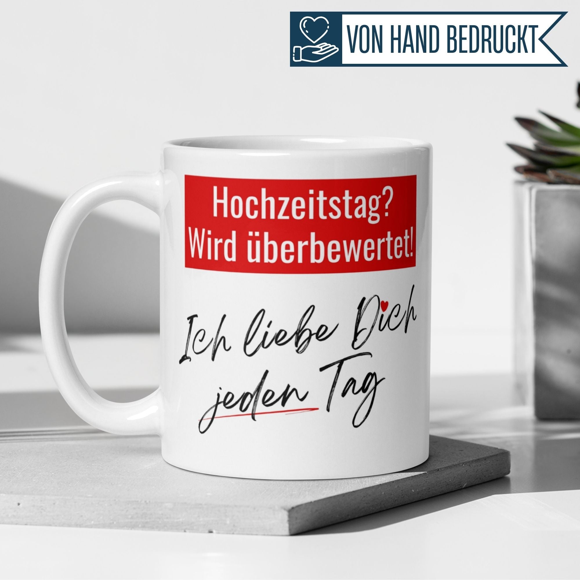 Momentals® Tasse mit Spruch "Hochzeitstag? Wird überbewertet! Ich liebe dich jeden Tag" in hellem Hintergrund.
