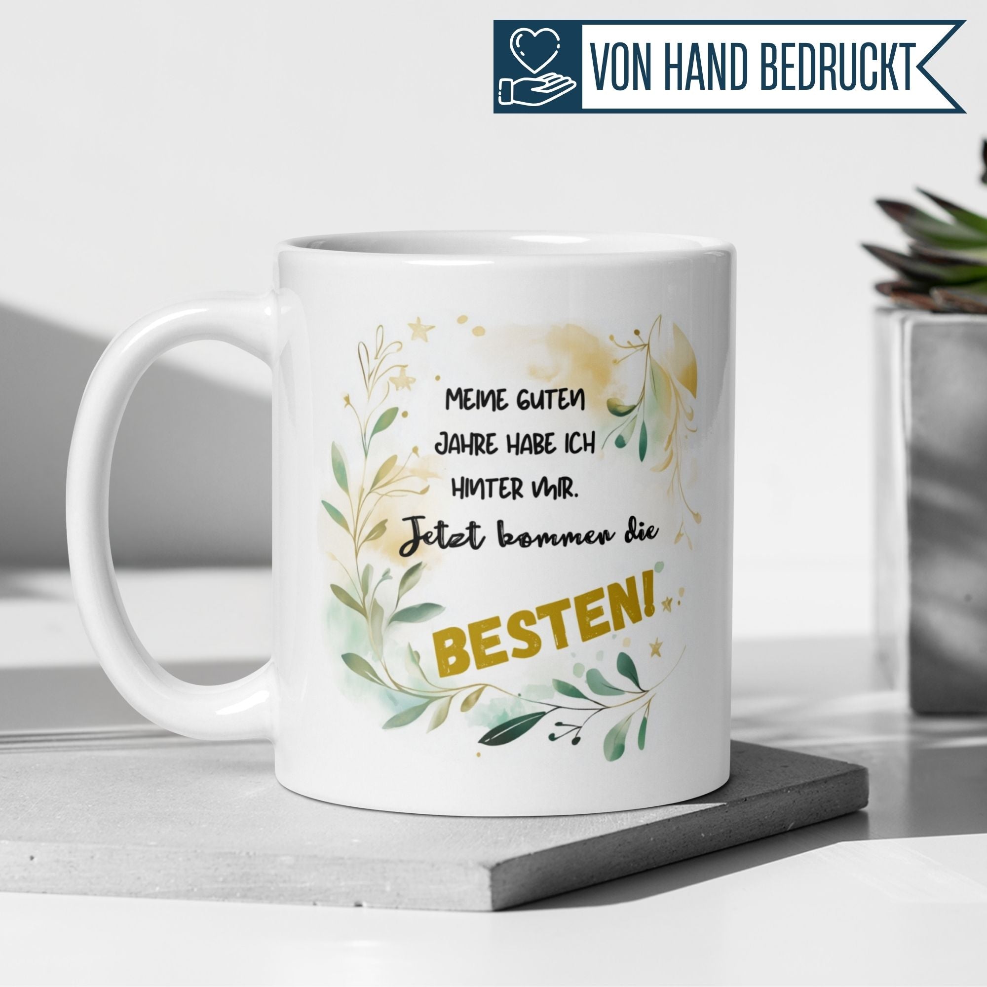 Momentals Tasse mit Aquarelldesign und Spruch: "Jetzt kommen die BESTEN!" für einen neuen Lebensabschnitt.