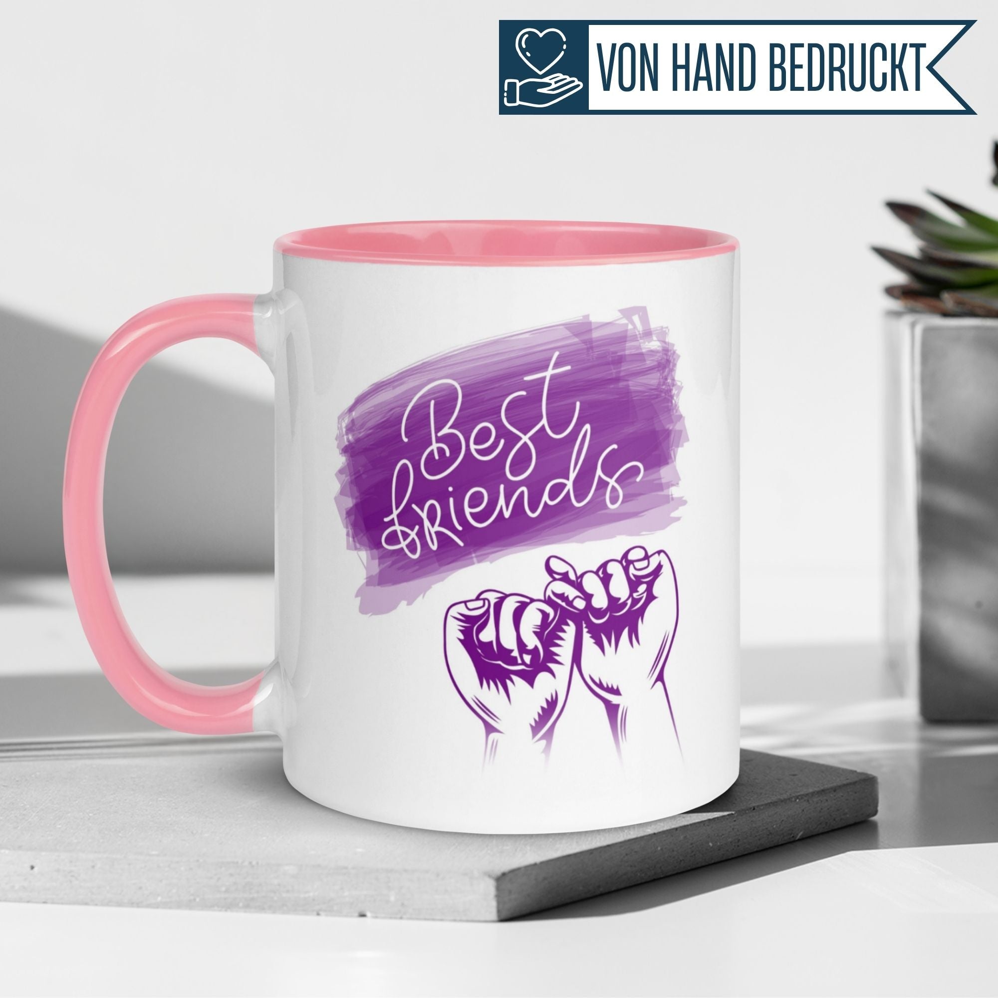 Momentals Tasse mit pinkem Griff und Best Friends Motiv im Pinky Promise Stil auf lila Hintergrund.