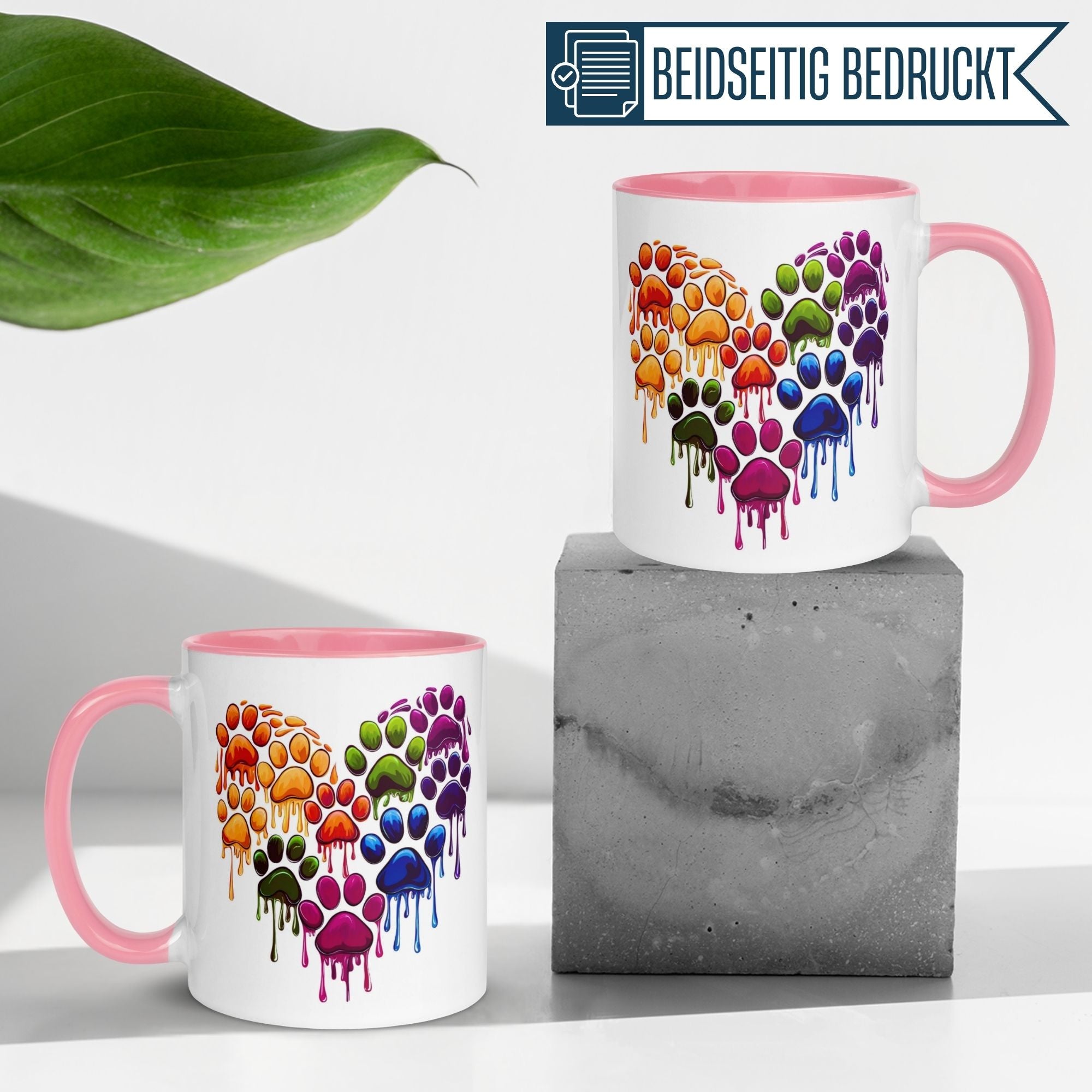 Bunte Katzenpfoten-Tasse mit Herzmotiv in Regenbogenfarben, beidseitig bedruckt auf pinkem Rahmen.