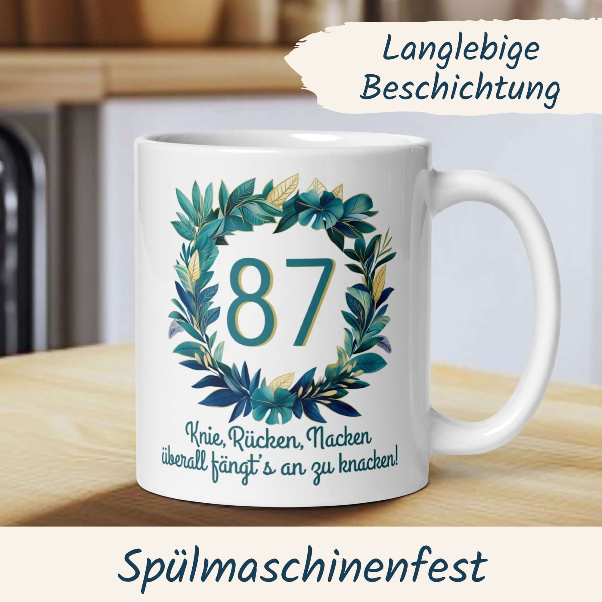 Witzige Tasse zum 87. Geburtstag mit floralem Kranz und Spruch zu Gelenkschmerzen.