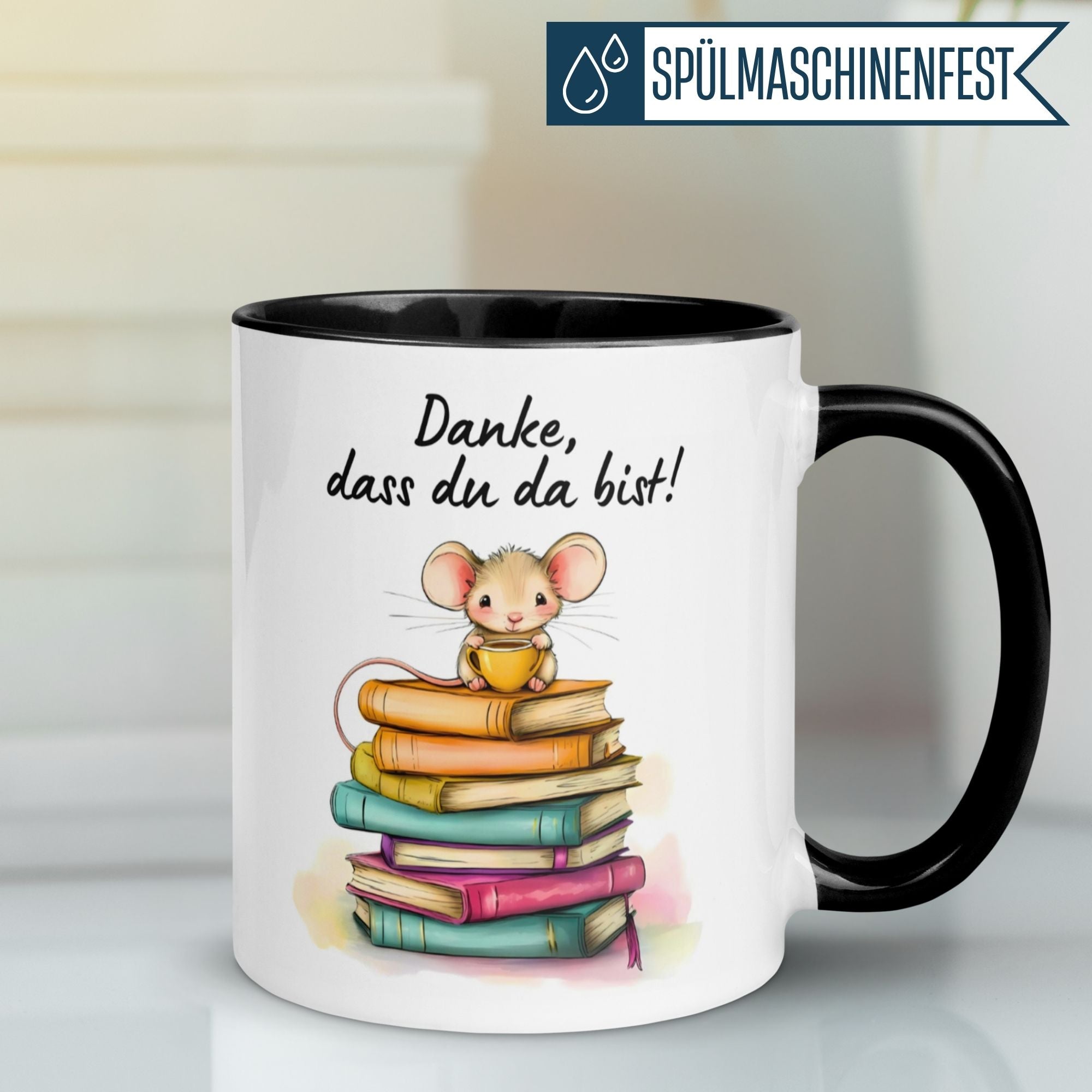 Momentals Tasse mit Mäuse-Motiv und Schriftzug 'Danke, dass du da bist' auf bunten Bücherstapeln.