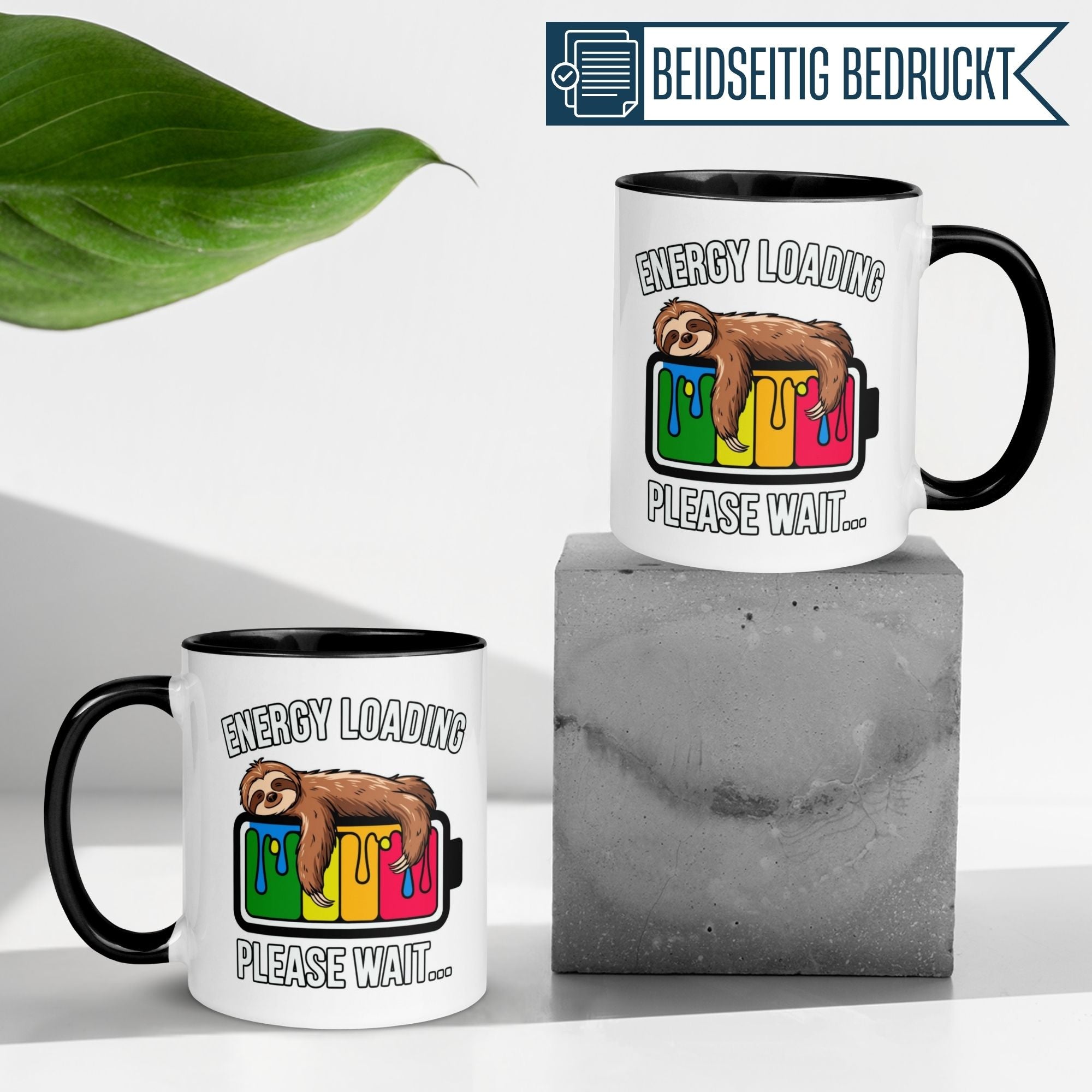 Momentals® Tasse mit Faultier und Spruch "Energy Loading – Please Wait" auf Betonunterlage.