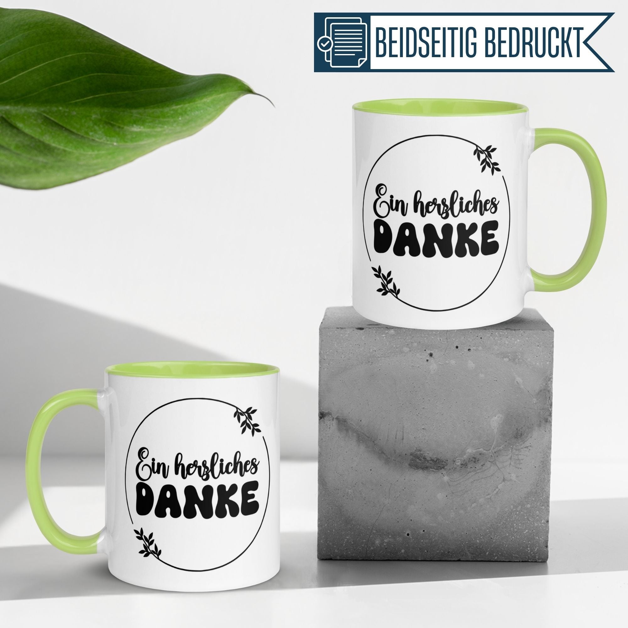 Momentals Tasse Dankeschön mit grünem Henkel, zeigt den Spruch 'Ein herzliches DANKE' in elegantem Design.
