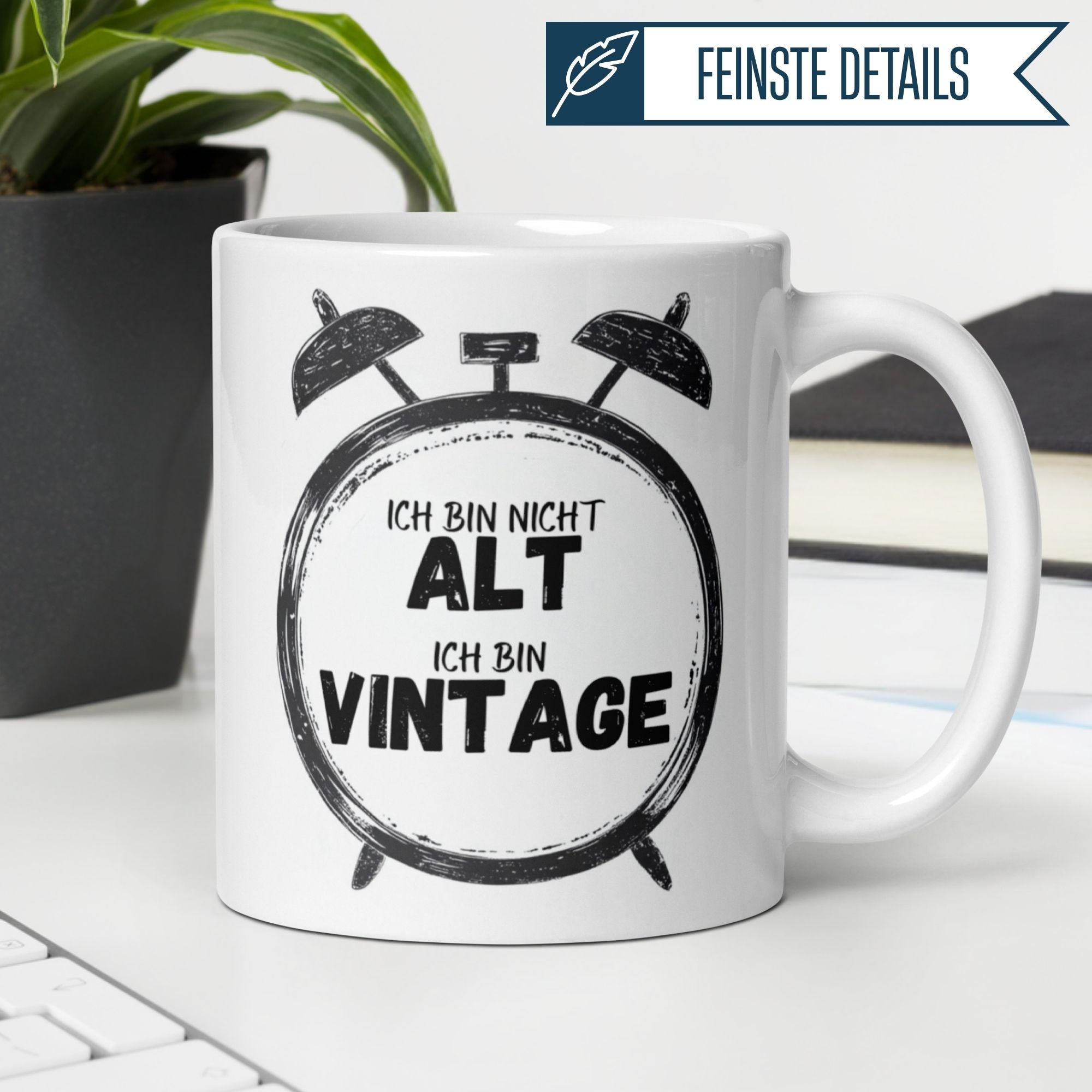 Momentals® Tasse mit Spruch "Ich bin nicht alt, ich bin Vintage" und Retro-Wecker-Design auf Schreibtisch.