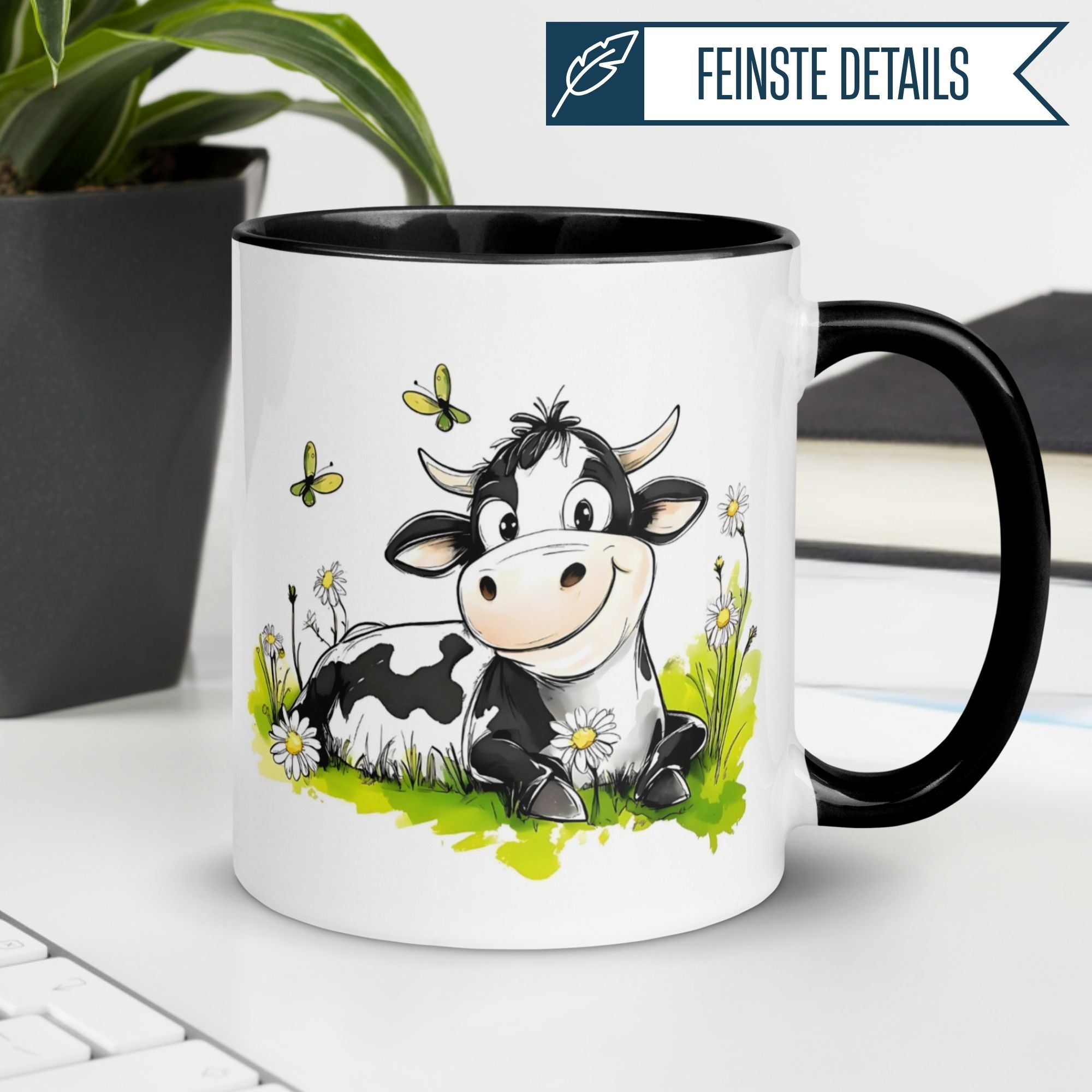 Schwarze Tasse mit lächelnder Kuh auf einer Blumenwiese, ideal für Morgenmuffel.