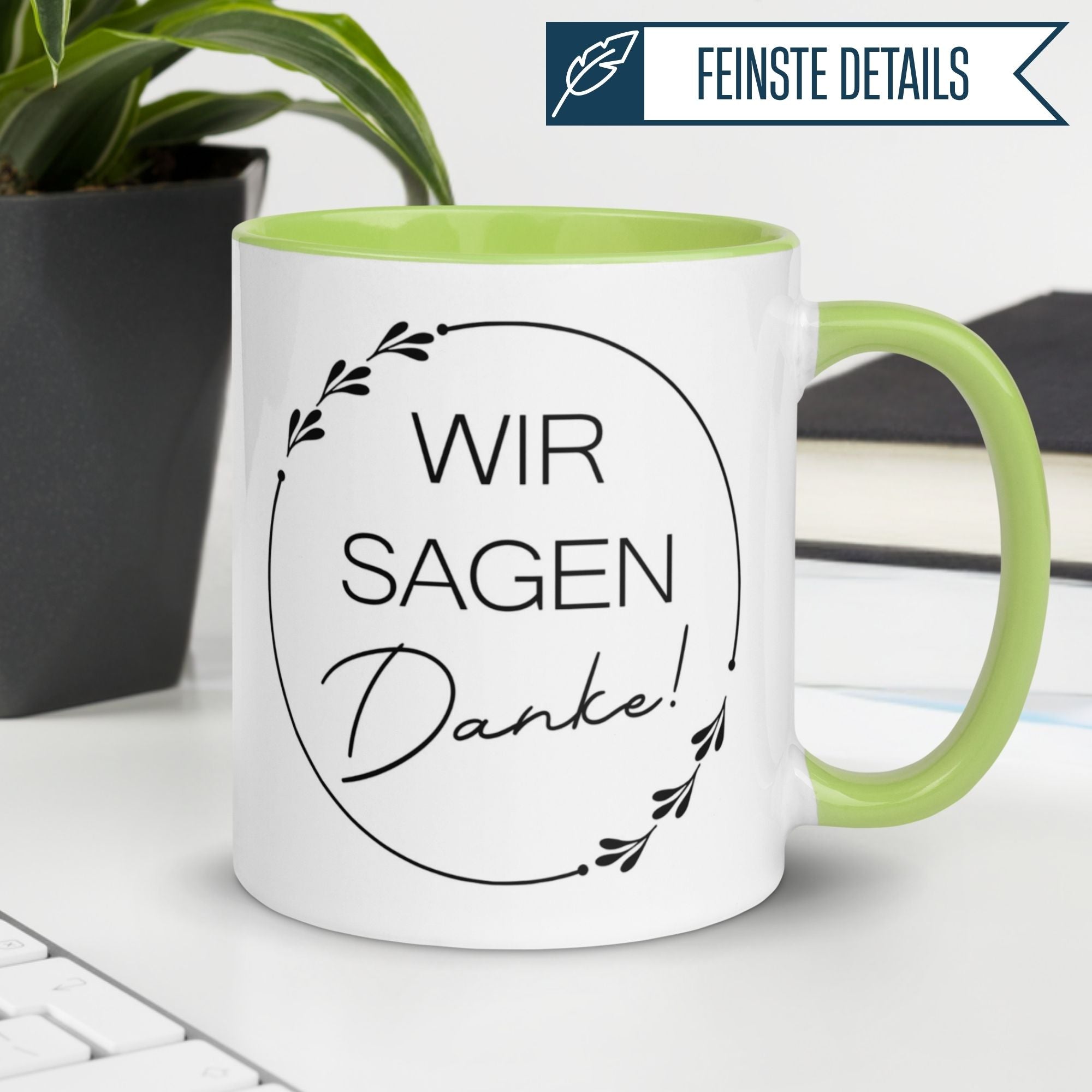 Momentals Tasse mit grünem Henkel und Dankespruch "Wir sagen Danke!" im modernen Design.