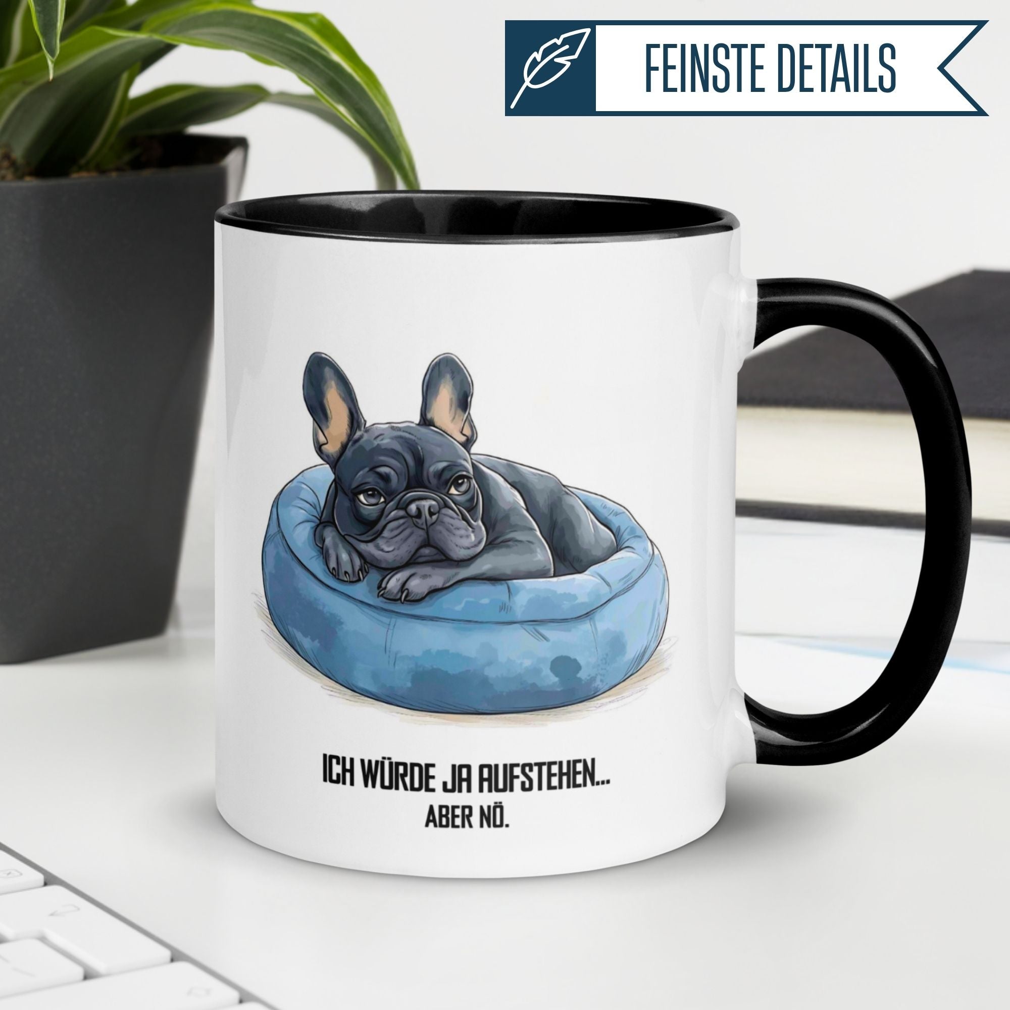 Mug with French bulldog illustration and text 'Ich würde ja aufstehen... aber nö.' on a cozy desk.