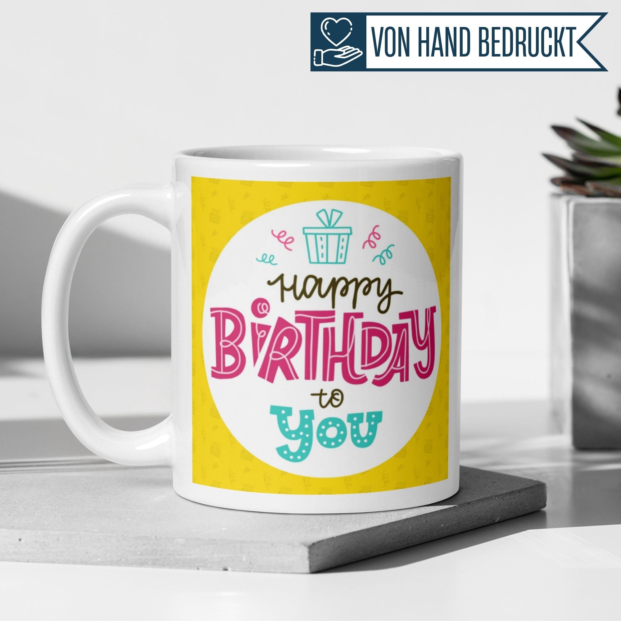 Bunte Geburtstagstasse mit 'Happy Birthday to you' auf gelbem Hintergrund und fröhlicher Typografie.