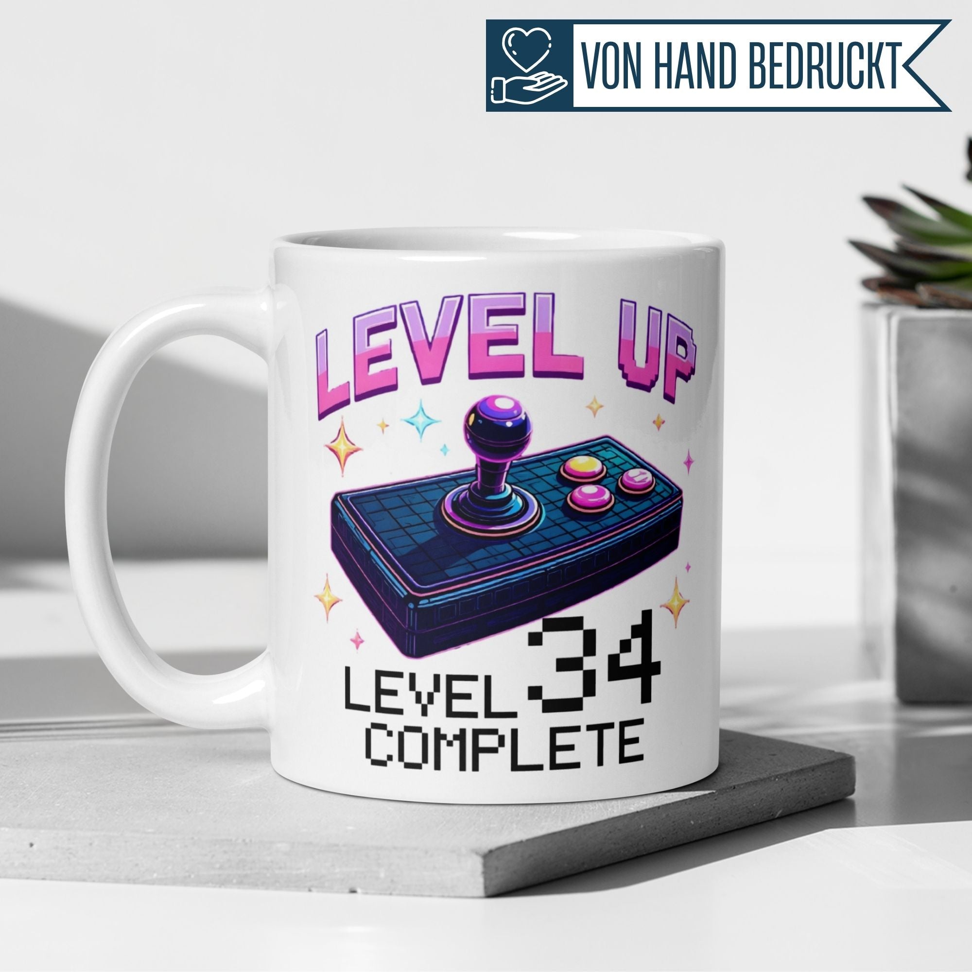 Bunte Gamer-Tasse mit Joystick-Illustration und Spruch 'Level Up! Level 34 Complete' für Geburtstagsfeier.