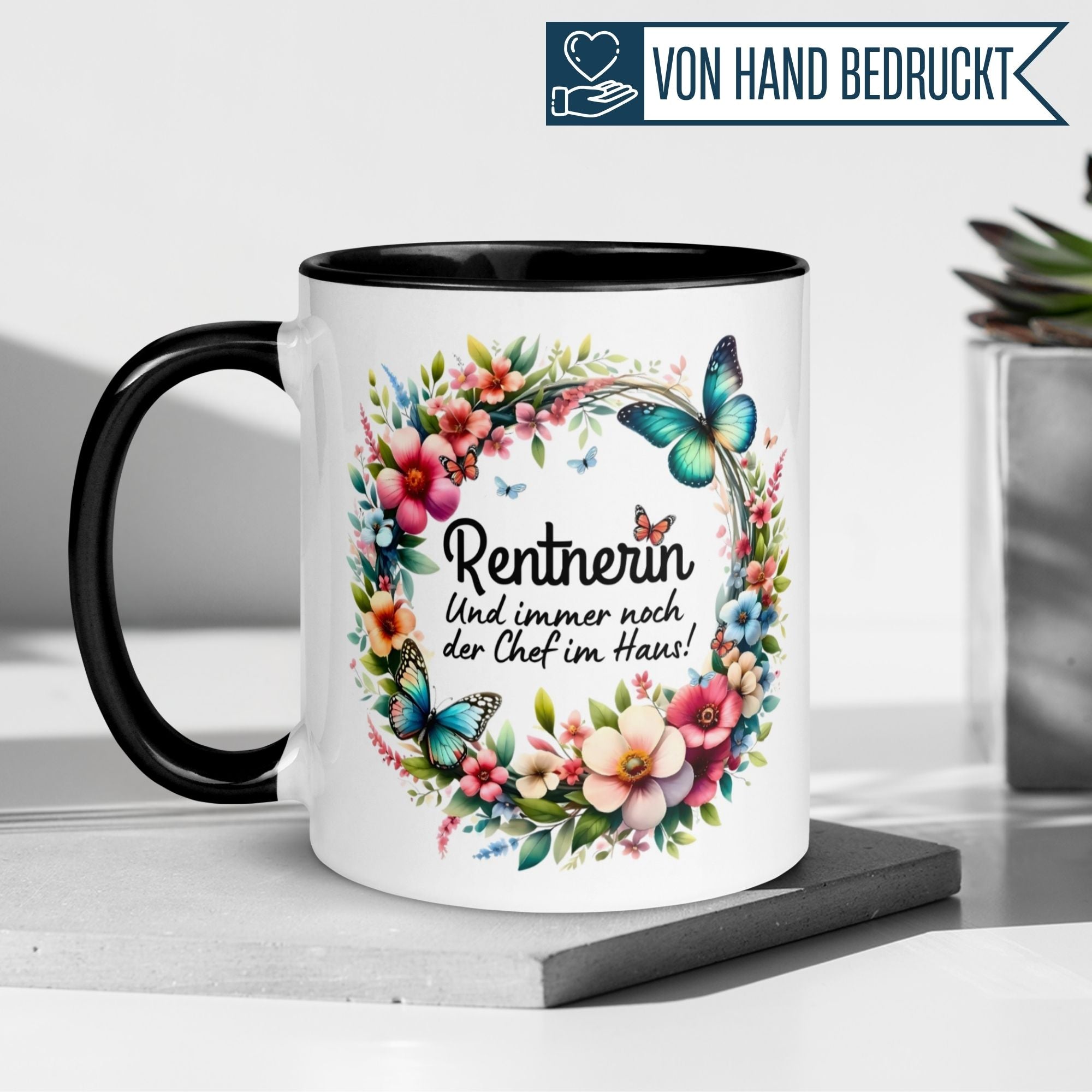 Bunte Tasse mit Spruch "Rentnerin – Und immer noch der Chef im Haus!" und Blumenkranz für frischgebackene Rentnerinnen.