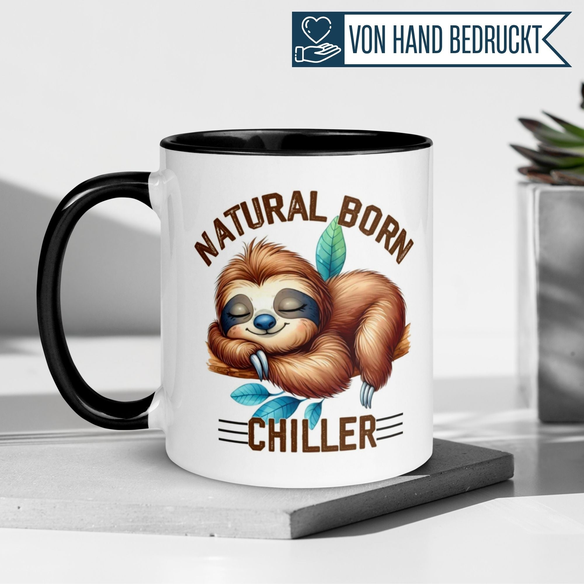 Momentals Tasse mit schlafendem Faultier und dem Spruch "Natural Born Chiller" auf einem stilvollen Tisch.