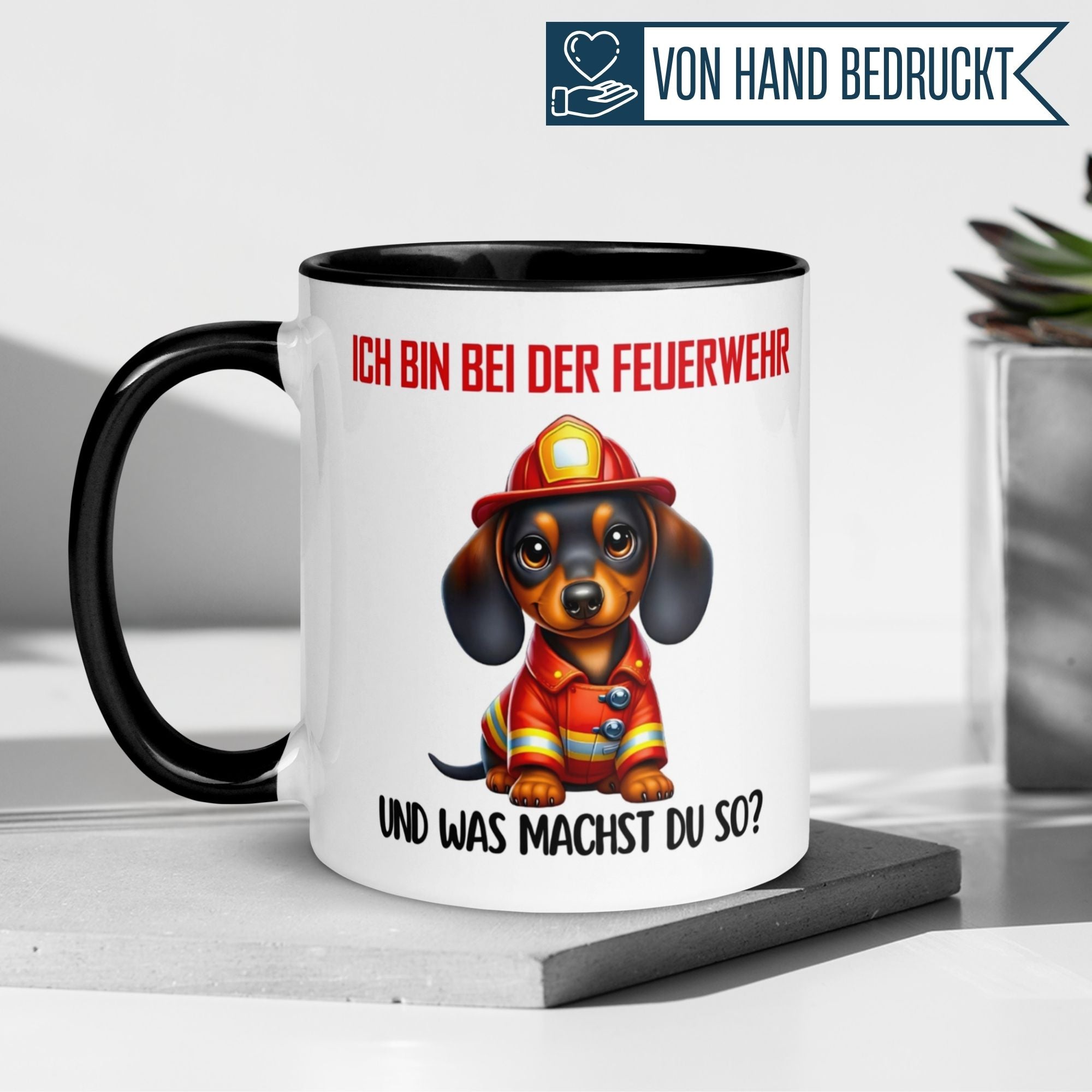 Farbenfrohe Tasse mit Dackel im Feuerwehr-Outfit und Spruch: 'Ich bin bei der Feuerwehr, und was machst du so?'. Ideal für Feuerwehrfans!