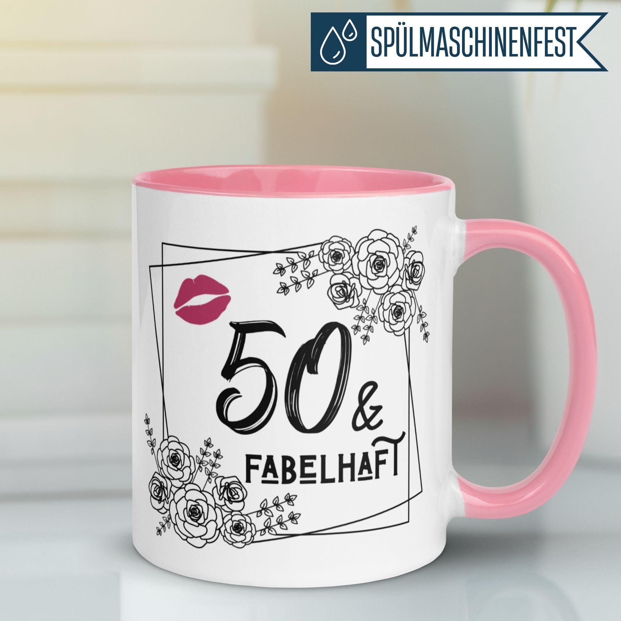 Momentals® Tasse für den 50. Geburtstag mit rosa Henkel, Blumen und witzigem Spruch '50 & Fabelhaft'.