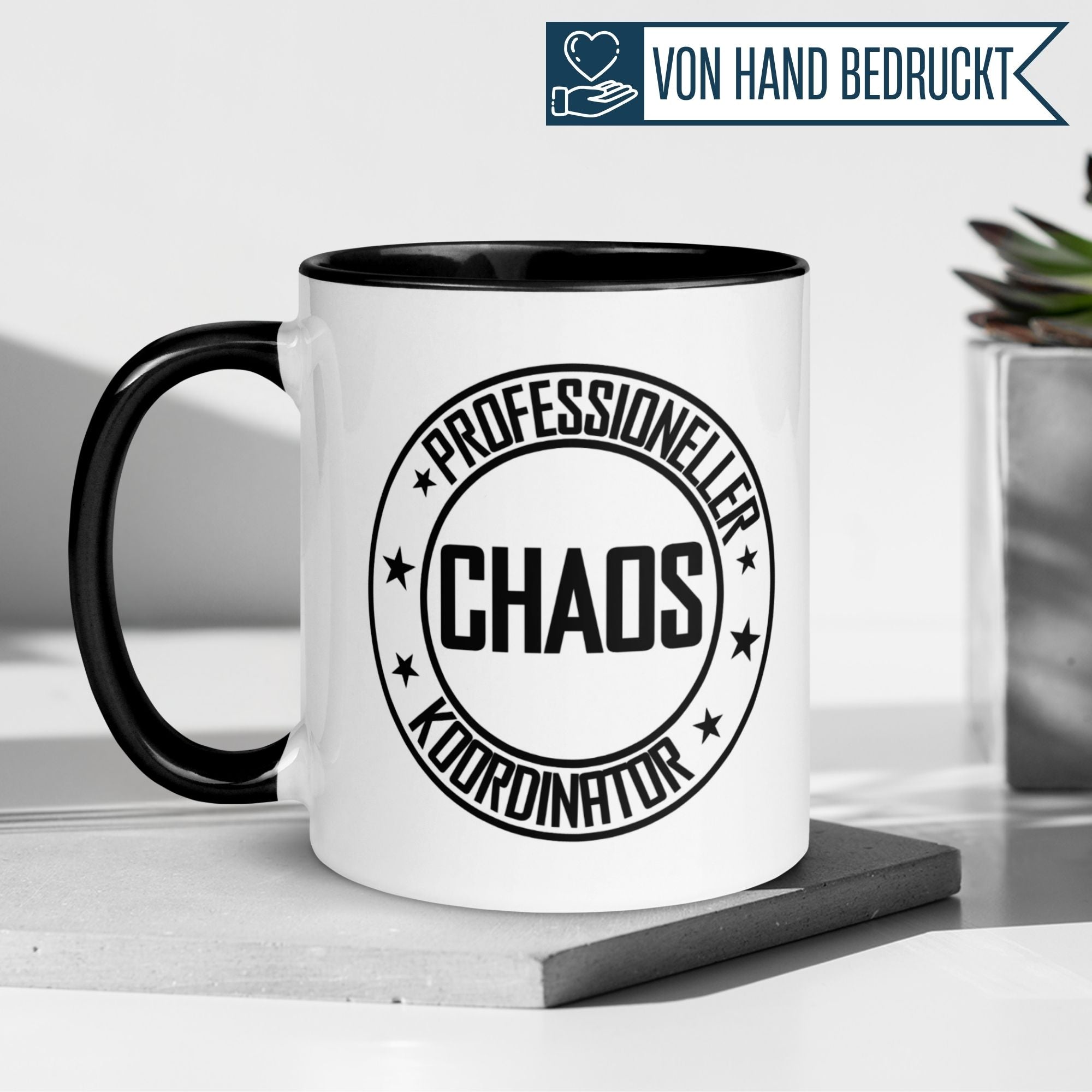 Weiße Tasse mit schwarzem Henkel, bedruckt mit dem Schriftzug "Professioneller Chaos Koordinator".