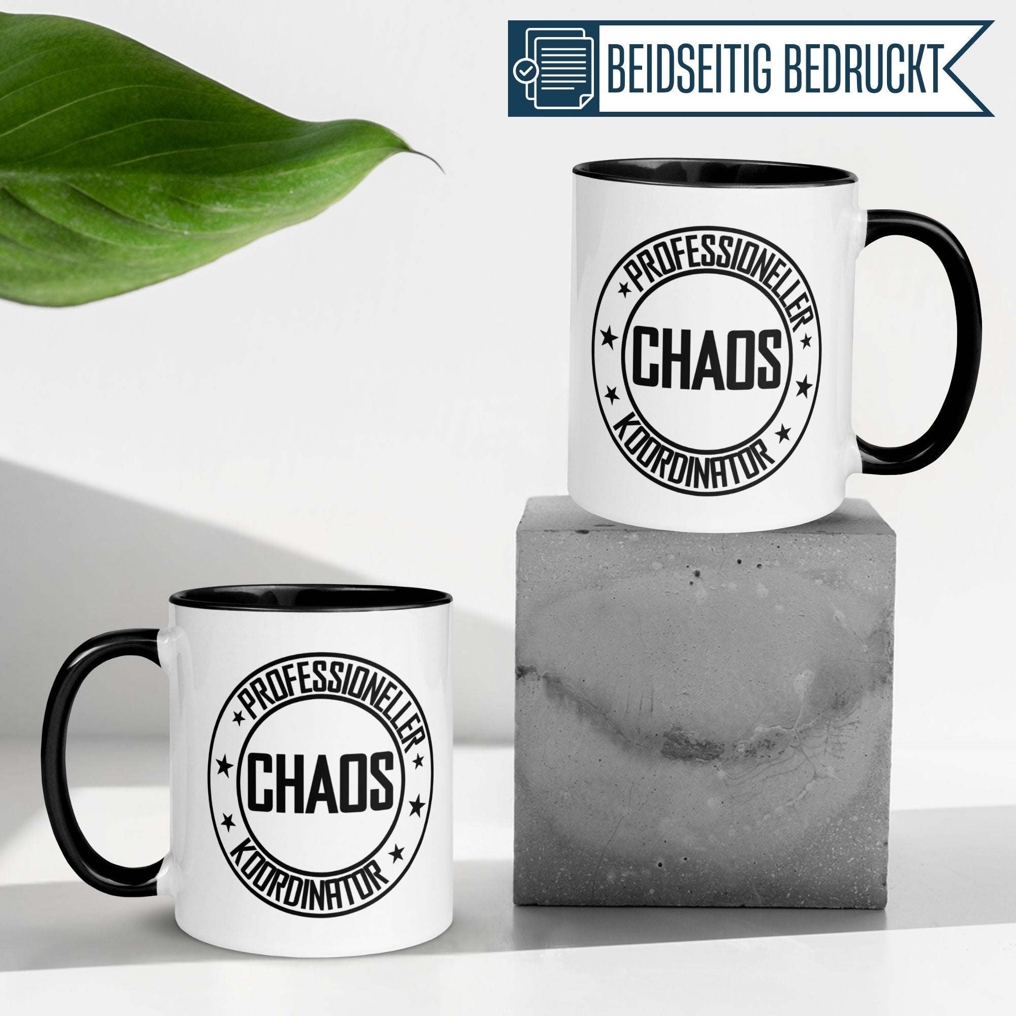 Zwei Tassen mit dem Aufdruck 'Professioneller Chaos Koordinator' auf einem grauen Betonblock.