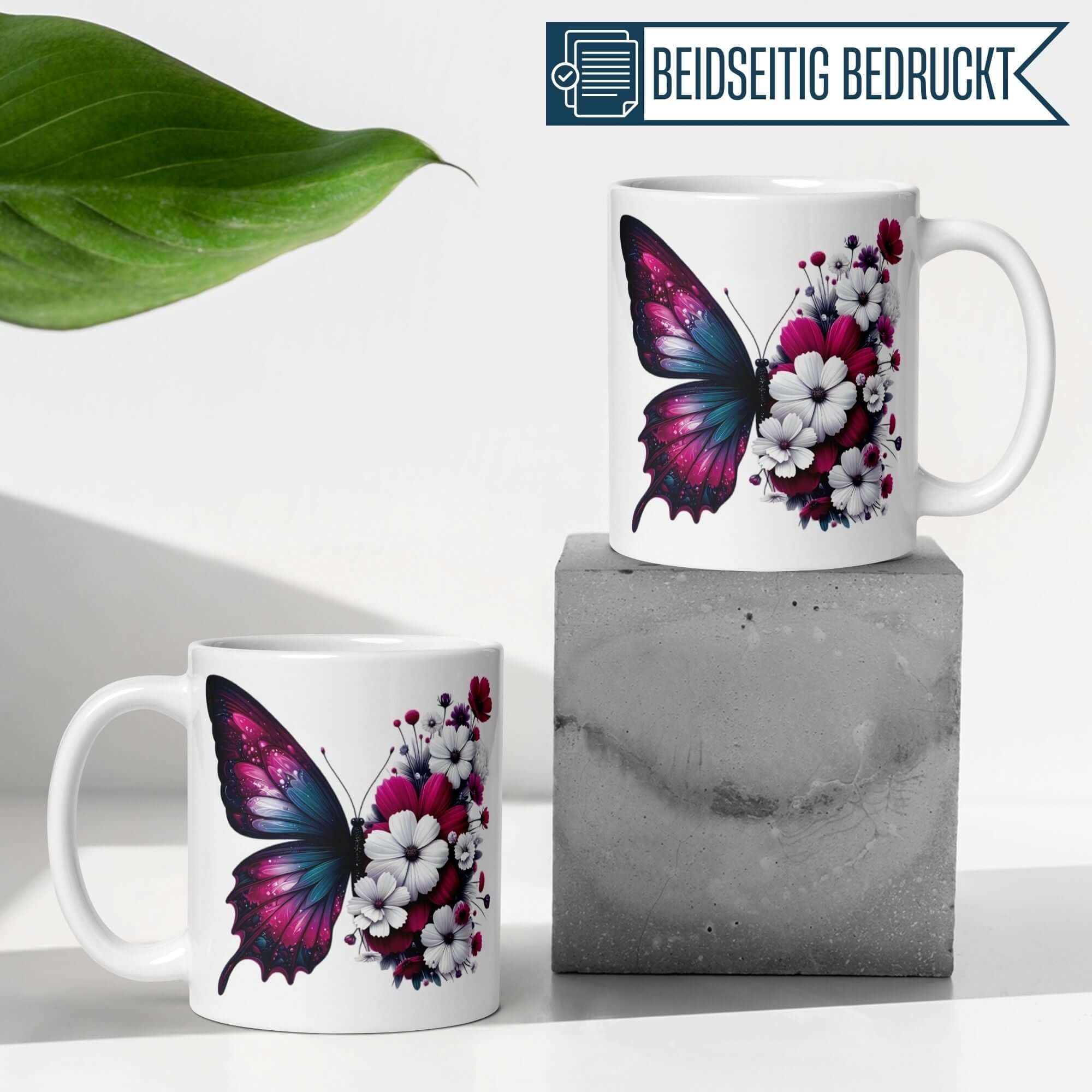 Momentals® Tasse mit Schmetterling und Blüten in Fuchsia, Pink und Weiß, auf Betonblock präsentiert.